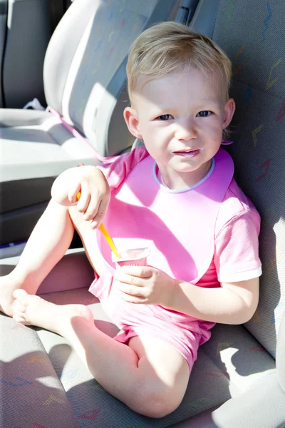 Little girl eating yogurt in the car — Stock Photo, Image