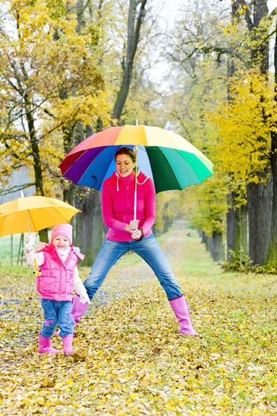 母亲和她的女儿在秋季小巷遮阳伞 — 图库照片