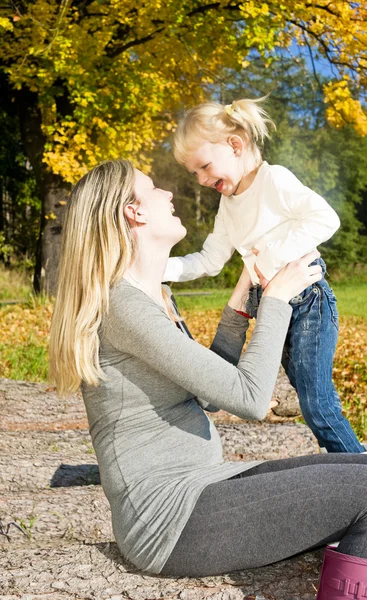 Pregnant woman with her little daughter in autumnal nature — Stock Photo, Image
