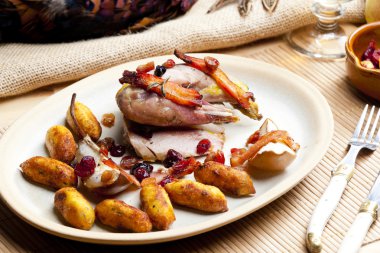 Baked pheasant with bacon, pear, raisins on brandy clipart