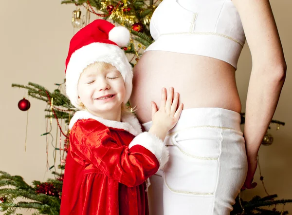 Kleines Mädchen und ihre schwangere Mutter zu Weihnachten — Stockfoto