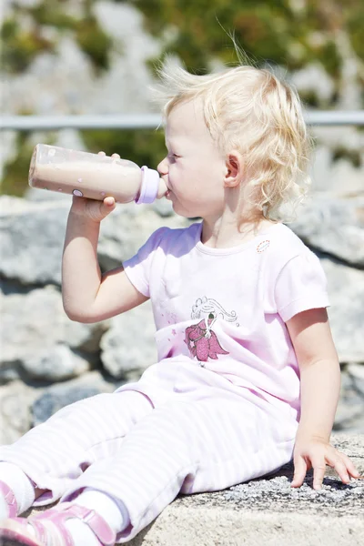Liten flicka med en flaska mjölk — Stockfoto