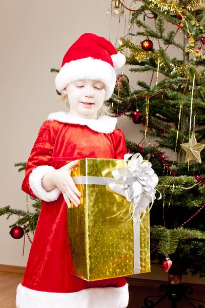 Kleines Mädchen als Weihnachtsmann mit Weihnachtsgeschenk Stockbild