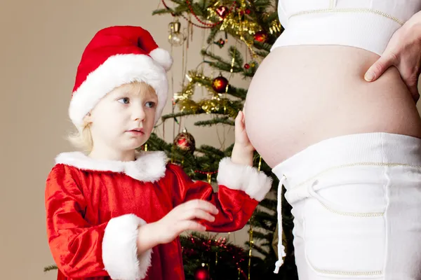 Portret van klein meisje en haar zwangere moeder door Kerstmis tre — Stockfoto