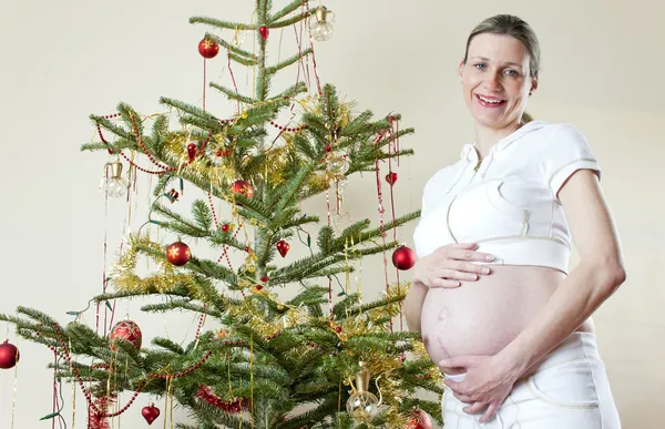 クリスマス ツリーが立っている妊娠中の女性の肖像画 — ストック写真