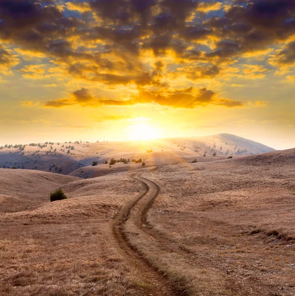 Horská silnice na západ slunce pozadí — Stock fotografie