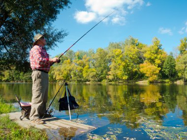 Senior fisherman catches a fish clipart