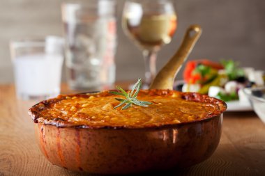 Baked moussaka dish on a wooden board clipart