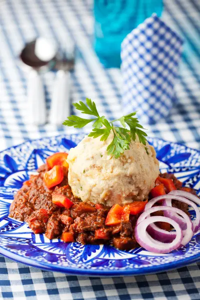 stock image Goulash with dumpling on a blue plate