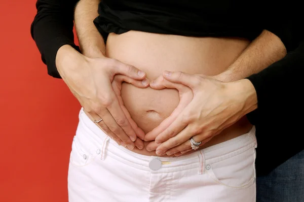 Schwangerer Bauch mit Herzhänden — Stockfoto