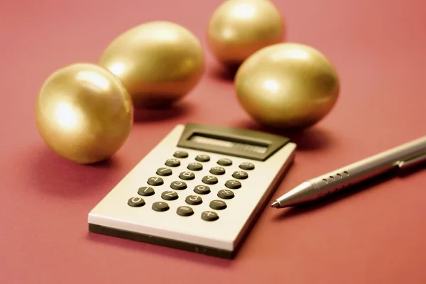 Uova d'oro con calcolatrice e penna — Foto Stock
