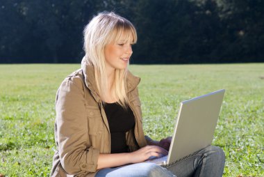 genç kadın bir çayır üstünde laptop