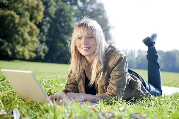 Ung kvinna med laptop på en äng — Stockfoto