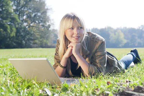 Junge Frau mit Laptop auf einer Wiese — Stockfoto