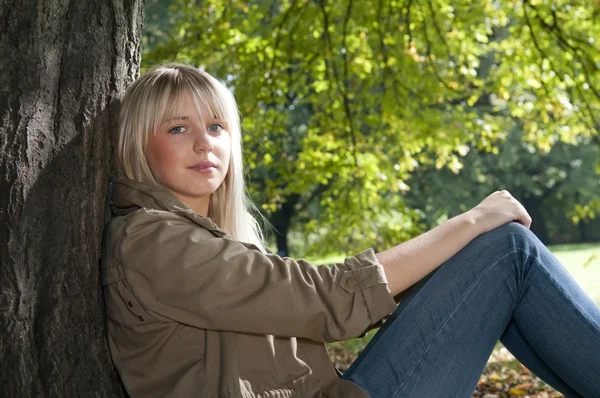 Ung kvinna sitter i parken — Stockfoto