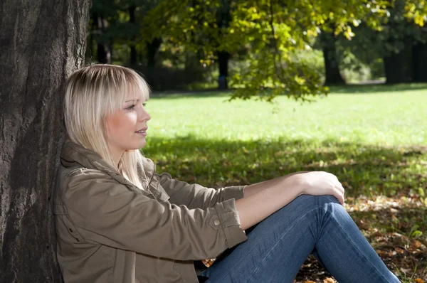 Jeune femme assise dans le parc — Photo