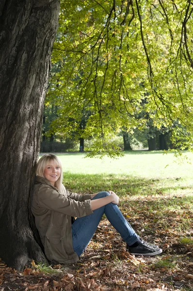 Mladá žena sedící v parku — Stock fotografie