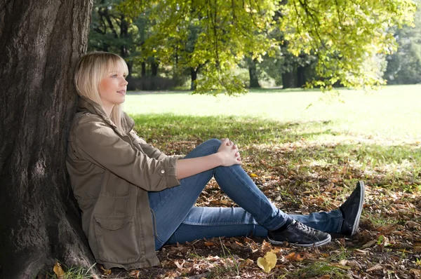 Mladá žena sedící v parku — Stock fotografie