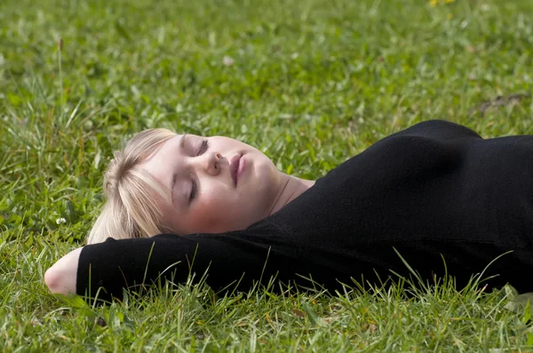 Ung kvinna liggande på en äng — Stockfoto