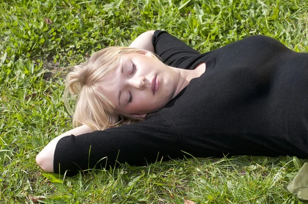 Jonge vrouw liggen op een weide — Stockfoto