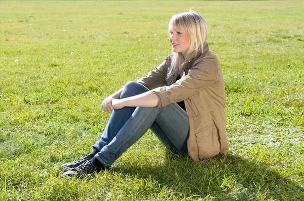 Young woman sitting on a meadow — Stock Photo, Image