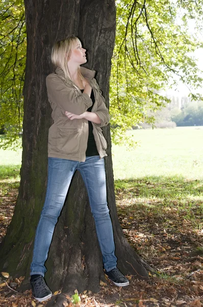Joven mujer de pie en un árbol — Foto de Stock