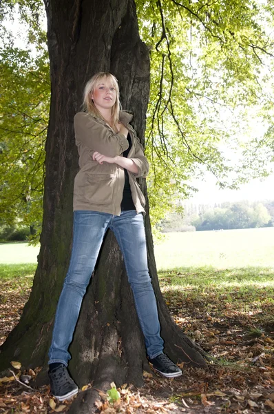 Młoda kobieta stoi na drzewie — Zdjęcie stockowe