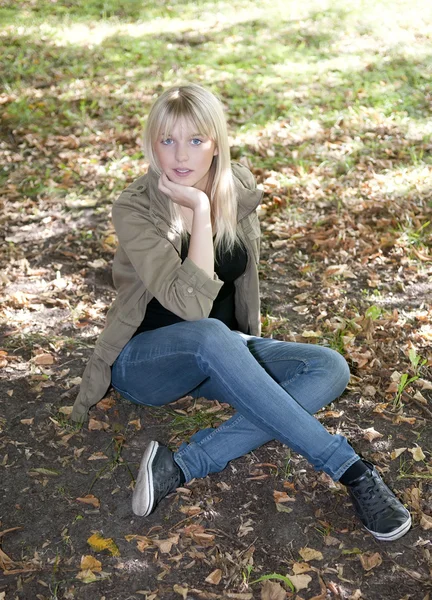 Bir çayır üzerinde oturan genç kadın — Stok fotoğraf