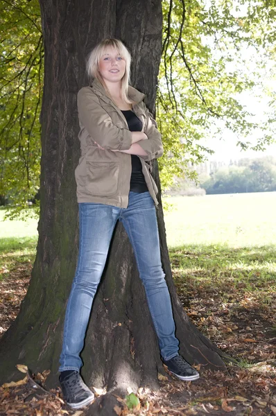 Giovane donna si erge su un albero — Foto Stock