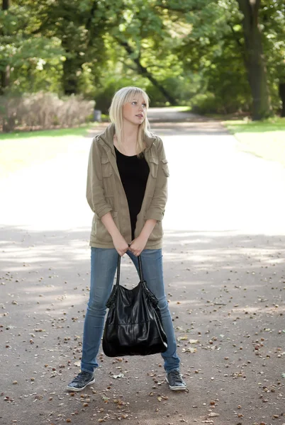 Mladá žena stojí v parku — Stock fotografie