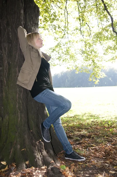 Νεαρή γυναίκα να στέκεται σε ένα δέντρο — Φωτογραφία Αρχείου