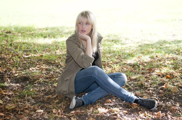 年轻女子坐在一片草地上 — 图库照片