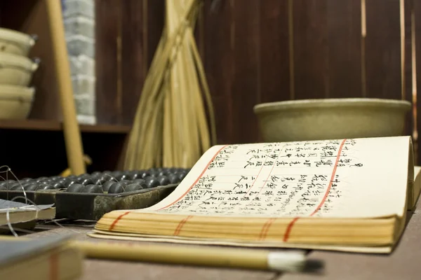 Počítadlo a kniha na stole v čínské staré dílně — Stock fotografie