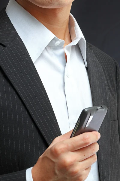 Бизнесмен в черном костюме работает над pda или смартфоном — стоковое фото