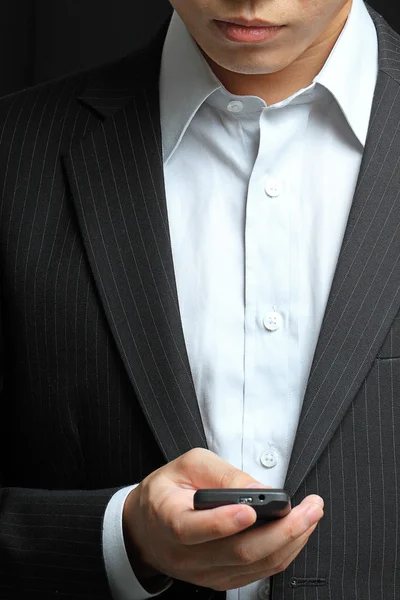 Hombre de negocios en traje negro trabajando en pda o teléfono inteligente —  Fotos de Stock