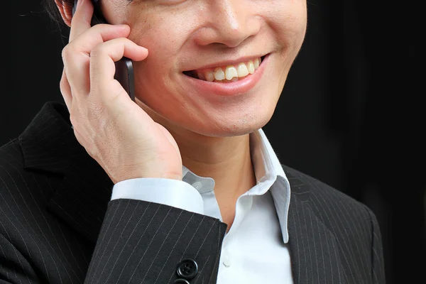 Portret van jonge man e praten op mobiele telefoon tegen een zwarte backgr — Stockfoto