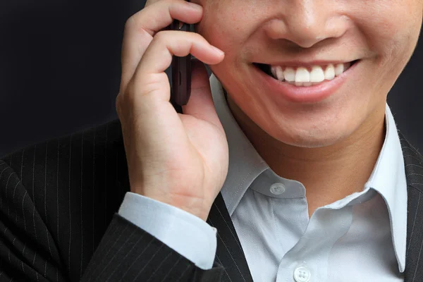 Portret van jonge man e praten op mobiele telefoon tegen een zwarte backgr — Stockfoto