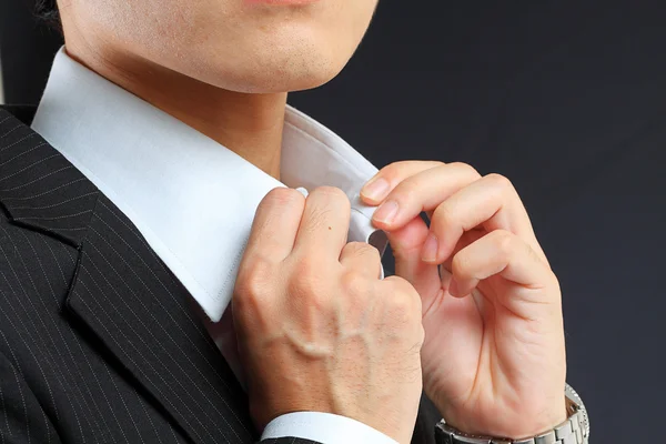 Young man adjusting his suit on a black background — Stock Photo, Image