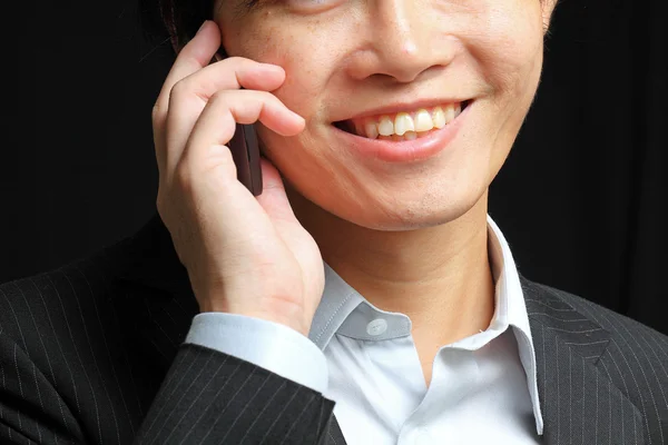 Portrait of e young man talking on mobile against a black backgr — Stock Photo, Image