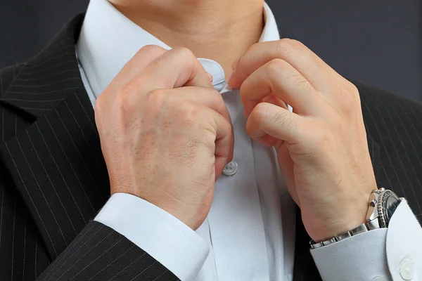 Young man adjusting his suit on a black background — Stock Photo, Image