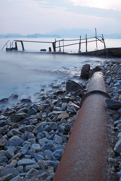 Old metal pipe and road to sea — Stock Photo, Image
