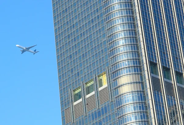Avión volar sobre el edificio moderno — Foto de Stock
