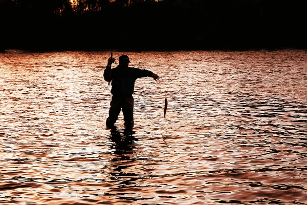 Siluetu rybáře tahání ryb — Stock fotografie