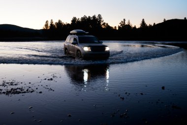 Car moves to fording the river in Mongolia clipart