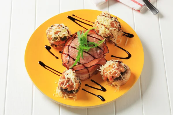 Mushrooms stuffed with ground meat and bacon-wrapped pork fillet — Stock Photo, Image