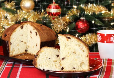 Panettone, whole and sliced, in front of a festive Christmas tre clipart