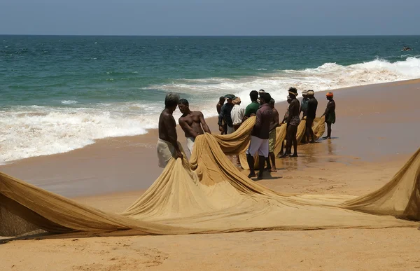 Fiskarna drar sitt fiske netto i kombinerade arbete ur havet — Stockfoto