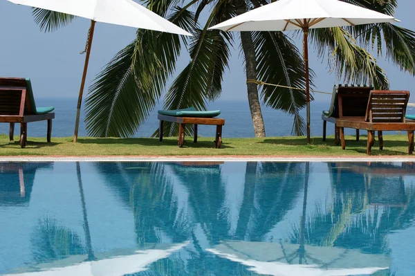 Palme da cocco che si riflettono nella piscina d'acqua vicino all'oceano — Foto Stock