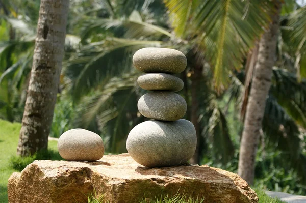 Stapel pebble stenen tegen de achtergrond van palmbomen en de zee — Stockfoto