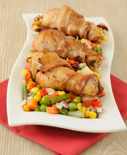 stock image Chicken leg wrapped in bacon with vegetables